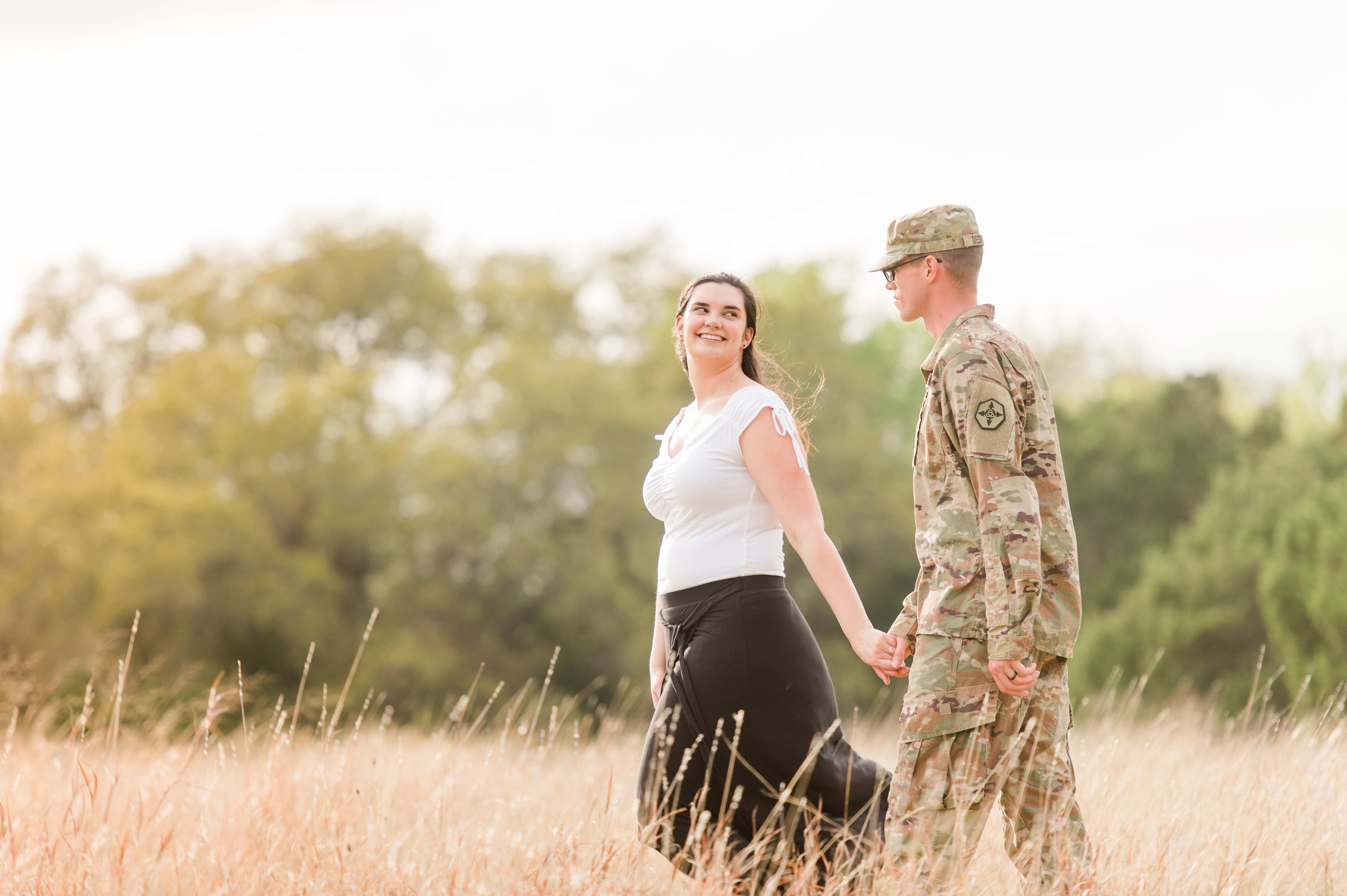 The military couple walks and looks up at each other lovingly.