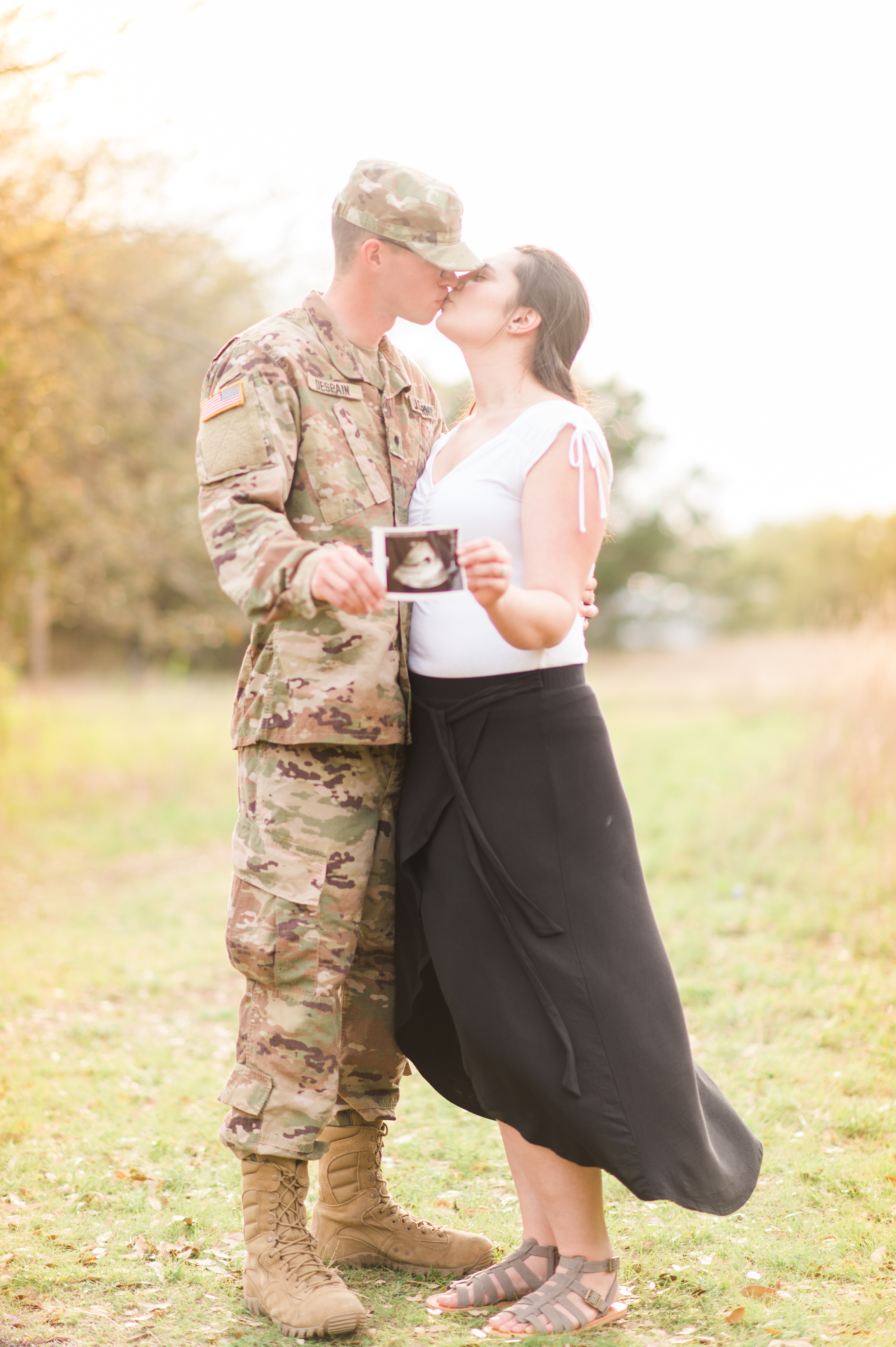 The couple gives each other a kiss as they hold their sonogram.