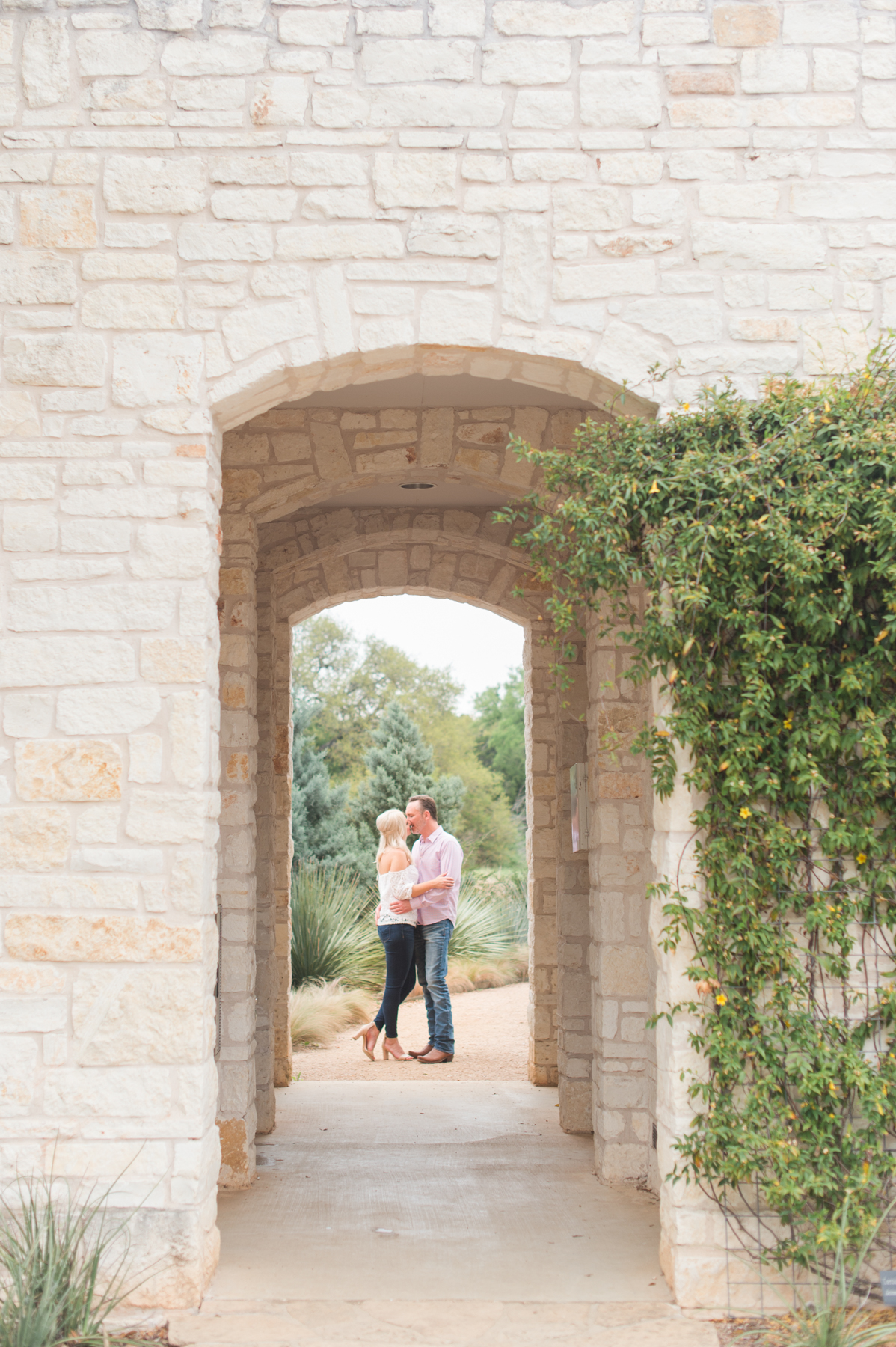 The couple kisses through the arch.