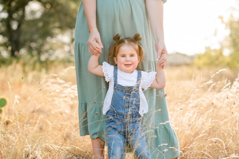 daughter-holds-mothers-hand-maternity-austin-tall-grass-field