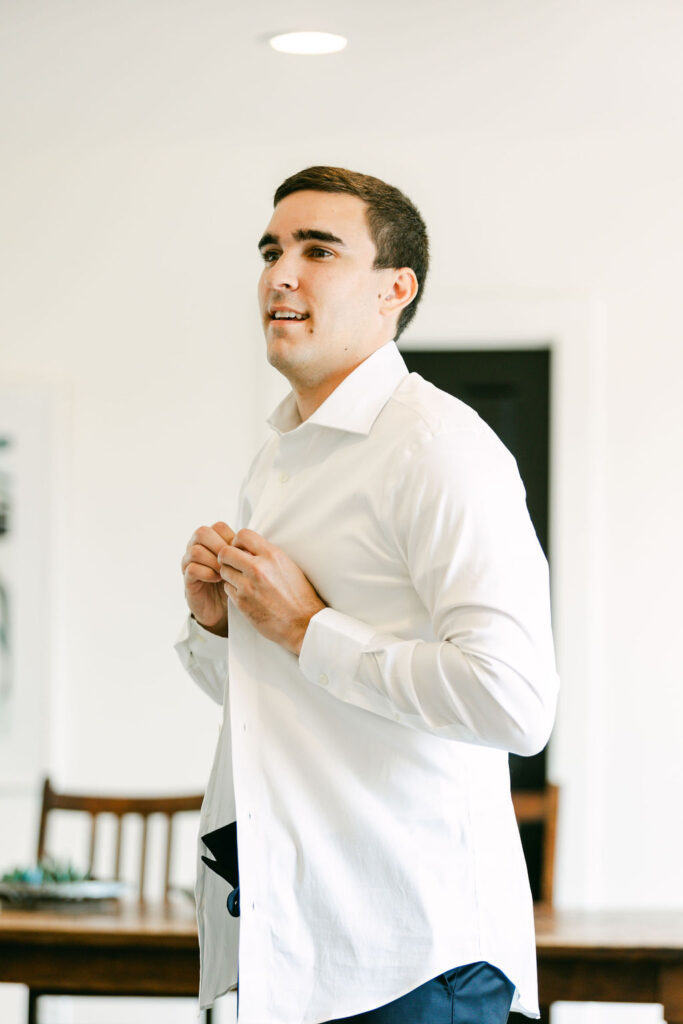 groom-buttoning-shirt-the-arlo-weddings