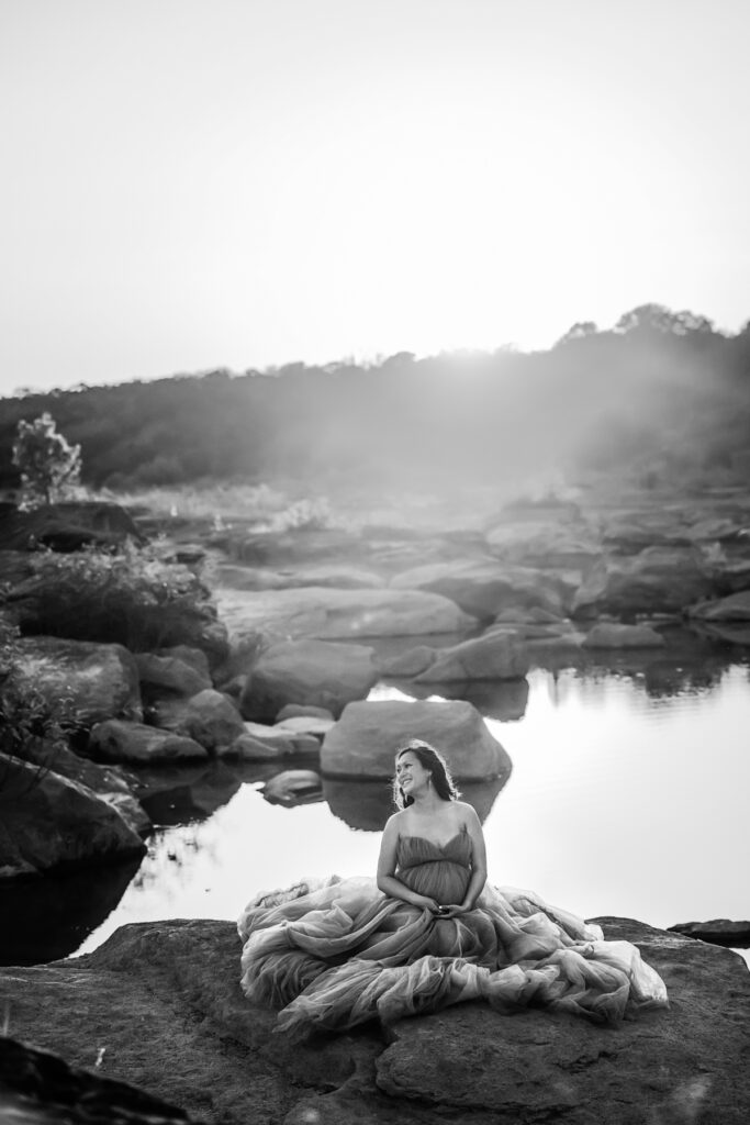 woman-pregnant-laughing-rocks-over-water-austin-maternity-dress