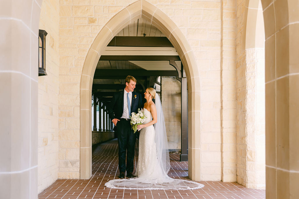 couple look at each together while posing underneath arch