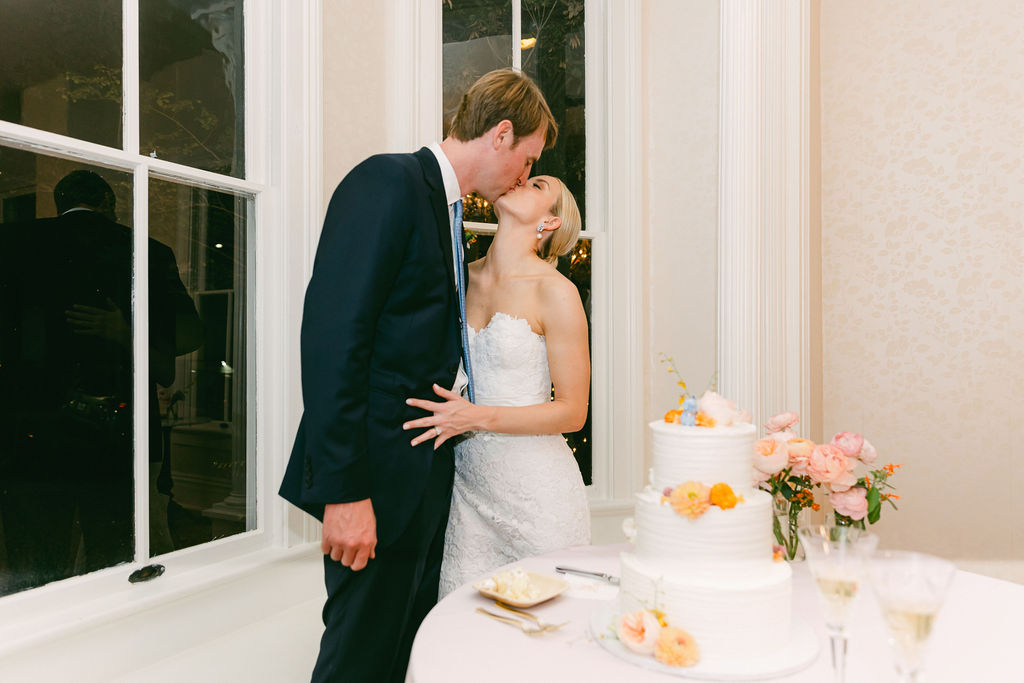 couple kiss before cutting cake
