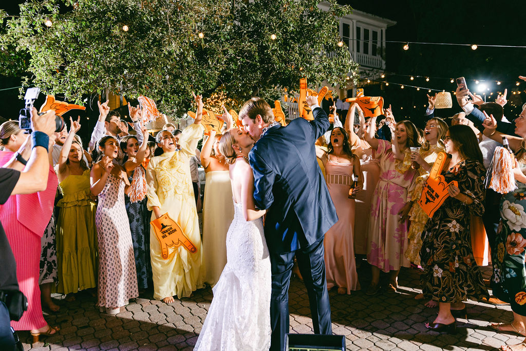 couple kiss surrounded by guests