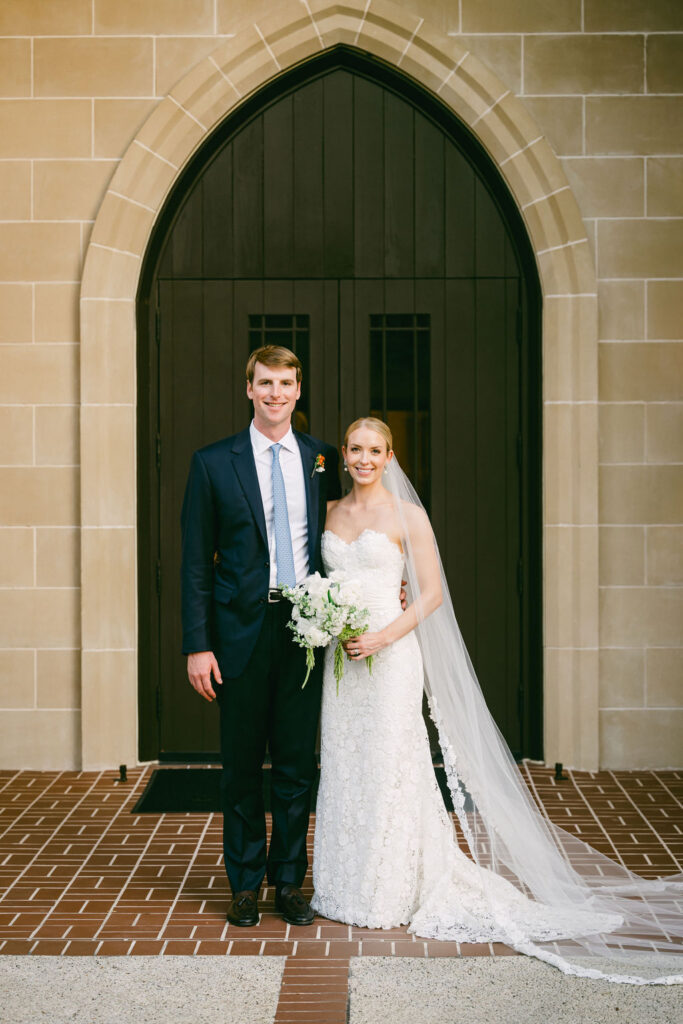 couple pose together in front of church doors