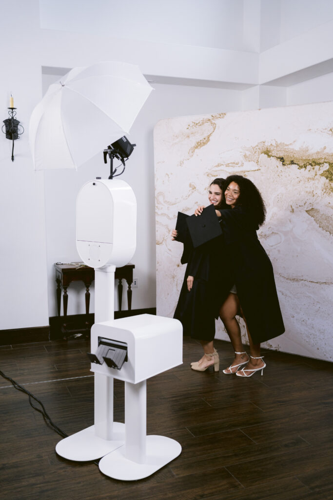 two girls posing with graduation attire in front of the photo booth