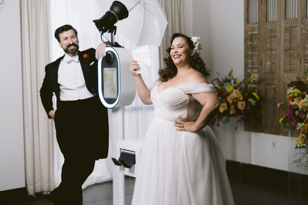 bride and groom pose with the photo booth rental
