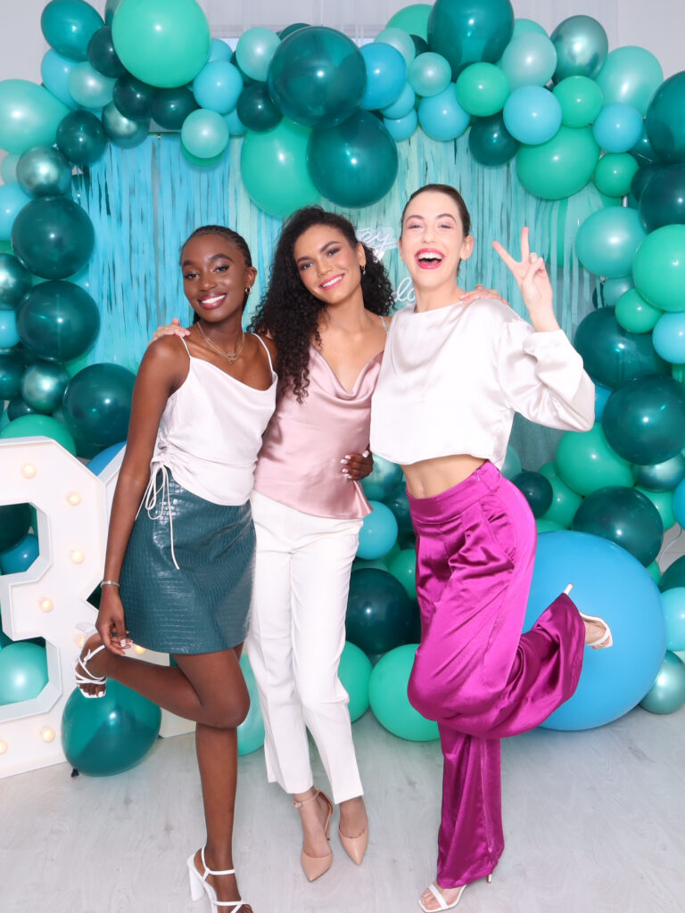 group of friends pose in front of photo booth during party