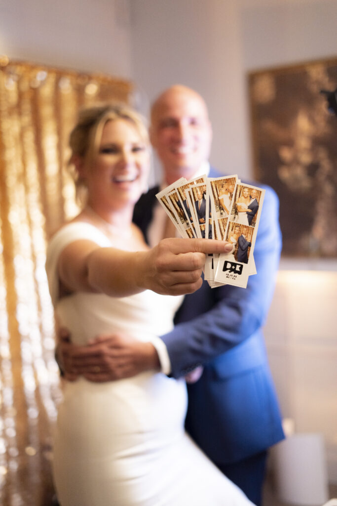 couple pose with the photos printed out from the Austin photo booth rental
