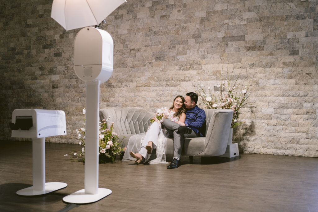 couple sits on couch to pose for the photo booth rental