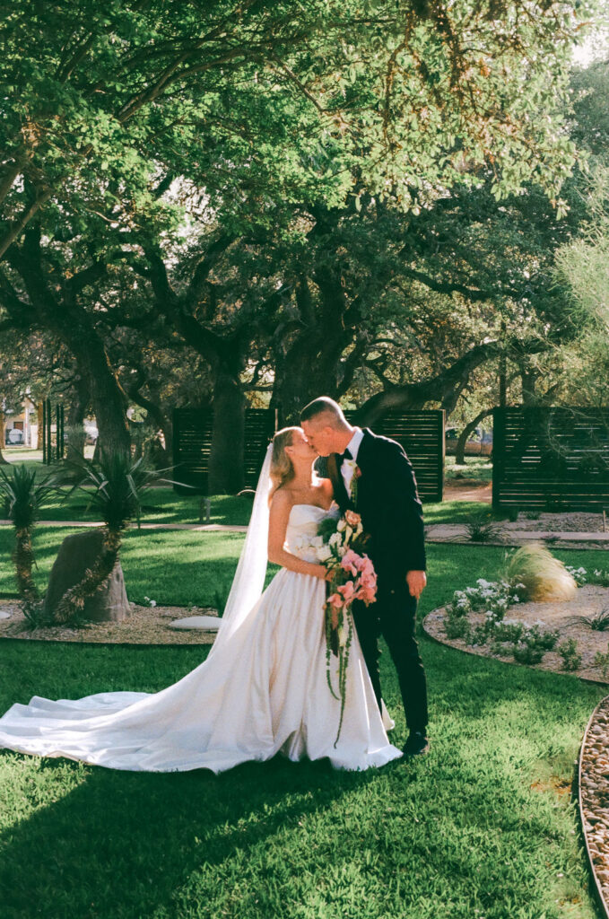 couple kiss for wedding film photography outside of venue