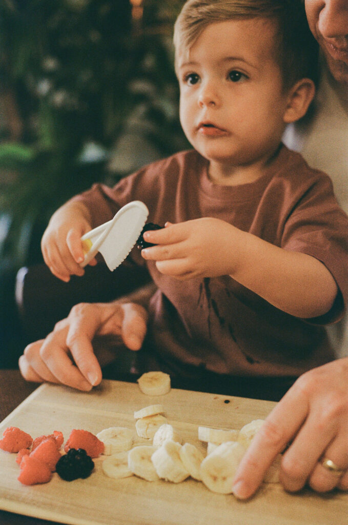 film photo of young child helping to cut fruit